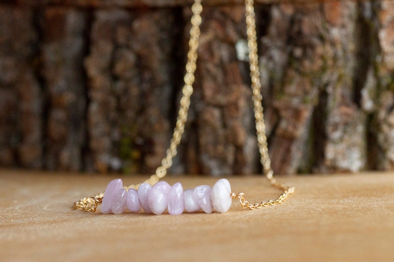 May include: A delicate gold chain necklace with a row of light purple and white gemstone chips.