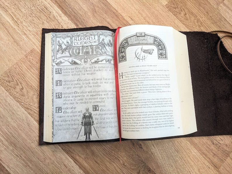 May include: An open book with a brown leather cover. The left page features a black and white illustration of a knight in armor with the text "ALEGHI CODES OF WAR" above the illustration. The right page features text from a book titled "COCOONS" with the text "Seven and a Half Years Ago" at the top of the page.