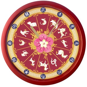Pode incluir: Um relógio circular vermelho com uma moldura dourada e um fundo branco. O mostrador do relógio apresenta os 12 animais do zodíaco chinês em ouro com seus caracteres chineses correspondentes. Uma flor rosa está no centro do mostrador do relógio.
