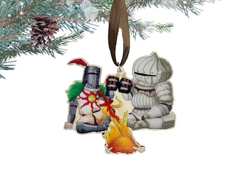 May include: A wooden Christmas ornament featuring a knight in white armor, a knight in gold armor with a sun symbol on his chest, and a fire. The knights are holding mugs and appear to be toasting each other.