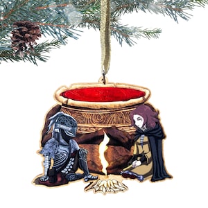 May include: A wooden Christmas ornament featuring a knight in armor and a woman sitting by a campfire. The knight is wearing a silver helmet and armor. The woman has long brown hair and is wearing a brown dress and a black cloak. The campfire is burning brightly and there is a large cauldron in the background.
