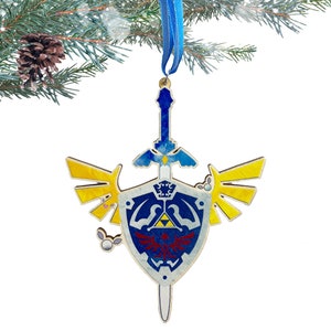 May include: A wooden Christmas ornament featuring the iconic Triforce symbol from the Legend of Zelda video game series. The ornament is painted in blue, yellow, and red, with a gold-colored sword and a blue ribbon for hanging.