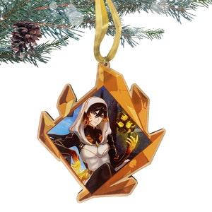 May include: A wooden Christmas ornament shaped like a crystal with a gold frame. The ornament features a character with black hair and a white and black outfit holding a glowing orb.