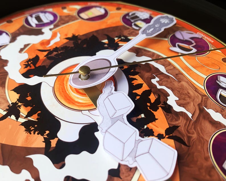 Pu&ograve; includere: Un quadrante decorativo a tema caff&egrave;. L'orologio presenta uno sfondo marrone e arancione con illustrazioni di oggetti legati al caff&egrave;. Le lancette dell'orologio sono un cucchiaio e una piccola forma bianca con tre cubetti di ghiaccio.