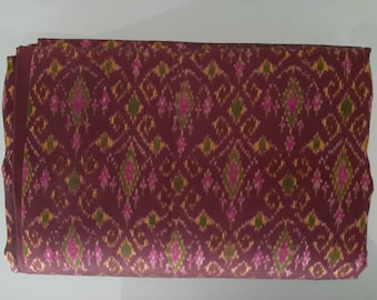 Thai mudmee silk textile. Dark Maroon background