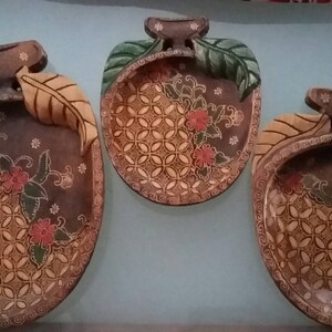 Könnte beinhalten: Drei Holzschalen mit aufwendigen Blumendesigns und einem braunen und goldenen Farbschema. Die Schalen sind apfelförmig und haben ein Blattdesign an der Seite.