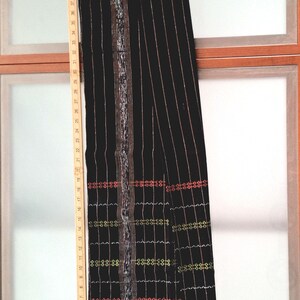 以下が含まれることがあります： 縦縞とカラフルな刺繍のディテールが施された黒いスカート