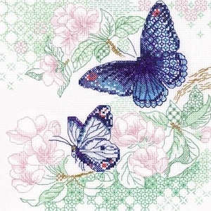 May include: A cross-stitch embroidery pattern featuring two butterflies and floral elements. One butterfly is dark blue with intricate grid-like wing details, while the other is smaller with light blue and purple tones. Pink flowers and green foliage surround them.
