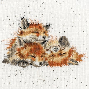 May include: Three fox cubs are curled up together sleeping on a white background with brown speckles. The cubs are orange and brown with black noses and eyes.