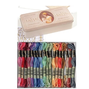 May include: A DMC embroidery floss set with a range of colourful threads. The set includes a metal tin with the DMC logo and a vintage illustration. The floss is arranged in a box, showcasing a spectrum of colours.