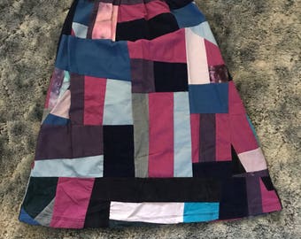 May include: A patchwork skirt with a variety of colors and patterns, including pink, blue, black, and white.