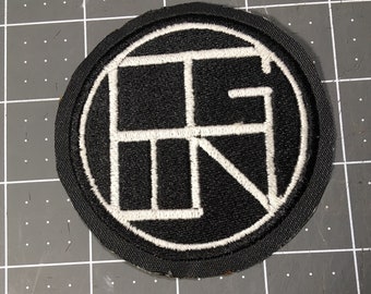 May include: Black and white embroidered patch with a circle design and the letter "R" inside. The patch is sewn onto a black fabric background.