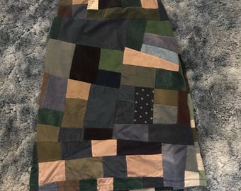 May include: A patchwork skirt made from different fabrics in shades of green, blue, brown, and beige. The skirt has a high waist and a straight silhouette.