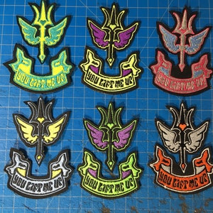 May include: Six embroidered iron-on patches with a winged trident design and the text "You Can't Me Up". The patches are in various colors, including green, purple, pink, yellow, orange, and black.