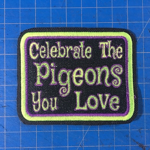 May include: A black embroidered patch with a green border and purple lettering that says "Celebrate The Pigeons You Love".