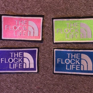 May include: Four embroidered patches with the text "The Flock Life" in white lettering on a black background. The patches are in pink, green, blue, and light blue.