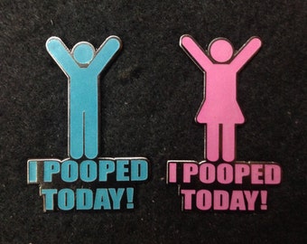 May include: Two enamel pins with the text "I Pooped Today!". One pin features a blue stick figure with arms raised, the other a pink stick figure with a skirt and raised arms. Both pins have a silver border.