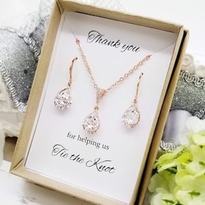 Puede incluir: Conjunto de collar y pendientes de oro rosa en una caja de regalo con una tarjeta que dice "Gracias por ayudarnos a atar el nudo".