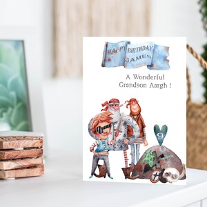 Könnte beinhalten: Eine Geburtstagskarte mit einer Aquarell-Illustration von drei Piraten. Die Karte sagt "Happy Birthday James" und "Ein wunderbarer Enkel Aaargh!" mit der Zahl 9 in einem Herz.