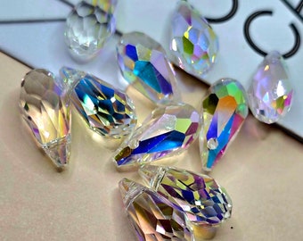 May include: A group of iridescent teardrop-shaped crystal beads. The beads are faceted and have a rainbow sheen.