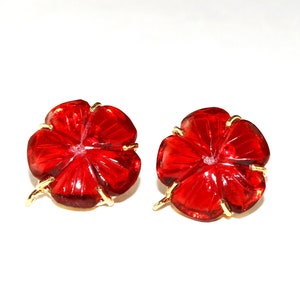 May include: A pair of red glass flower-shaped earrings with gold accents.