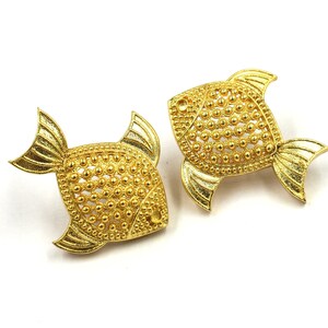 May include: A pair of gold fish-shaped earrings with a textured surface.