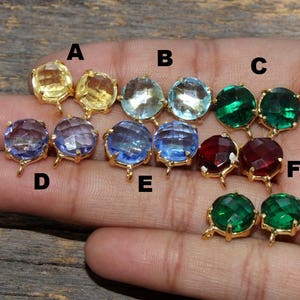 May include: Assortment of 10 gold-tone earring settings with various colored glass stones. The stones are in shades of blue, green, red, and yellow. The settings are labeled A through F.