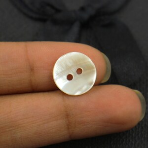 May include: A white mother of pearl button with two holes.