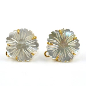 Può includere: Un paio di orecchini in madreperla bianca con un design a forma di fiore color oro.