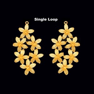 May include: A pair of gold-tone earrings with a single loop and a floral design. The earrings are made of metal and have a delicate, feminine look.
