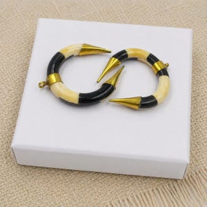 Peut inclure: Deux pendentifs en forme de croissant compos&eacute;s de segments altern&eacute;s de couleur cr&egrave;me et noire. Chaque pi&egrave;ce est agr&eacute;ment&eacute;e d'embouts en m&eacute;tal dor&eacute; poli aux deux extr&eacute;mit&eacute;s et comprend un petit anneau circulaire pour la fixation.