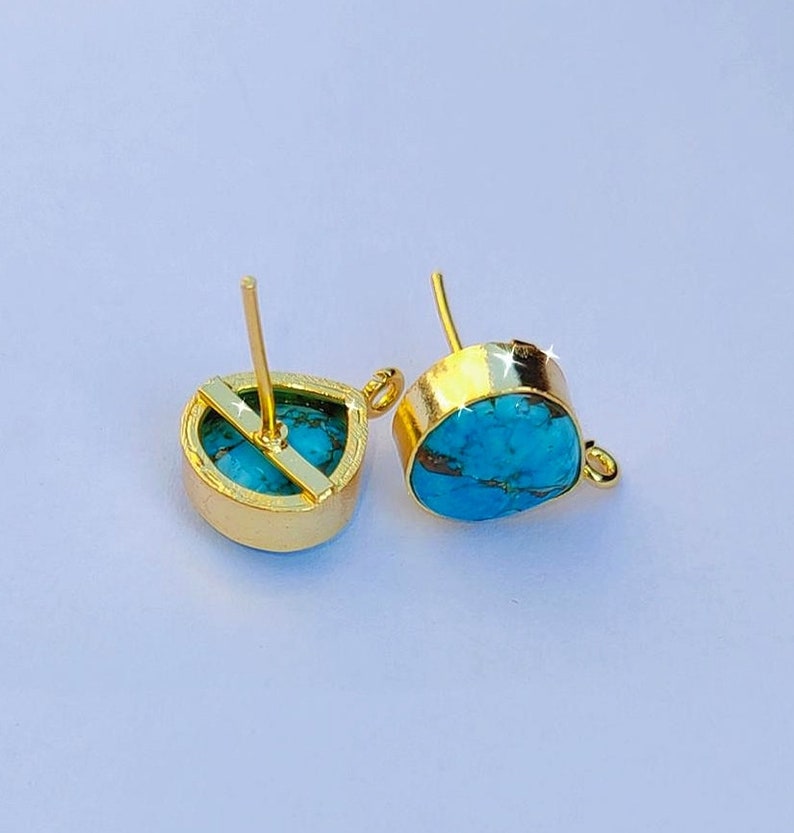 May include: A pair of gold-tone earrings with turquoise teardrop-shaped stones. The earrings have a post back and a small loop on the side.