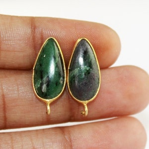 Puede incluir: Un par de pendientes de piedra preciosa verde y negra con engastes de oro. Los pendientes tienen forma de lágrima y tienen un pequeño bucle en la parte superior para sujetarlos a un gancho.