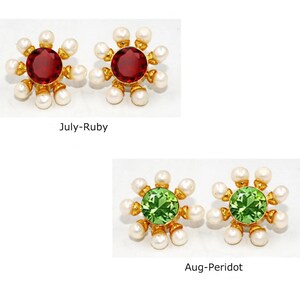 Peut inclure: Deux paires de boucles d'oreilles en or avec un motif floral. Chaque boucle d'oreille a une pierre pr&eacute;cieuse rouge ou verte au centre entour&eacute;e de perles blanches. Le texte "July-Ruby" et "Aug-Peridot" est sous les boucles d'oreilles.