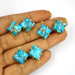 May include: Five square turquoise gemstone pendant connectors with gold-toned metal settings and loops. The turquoise has a marbled pattern with gold flecks.