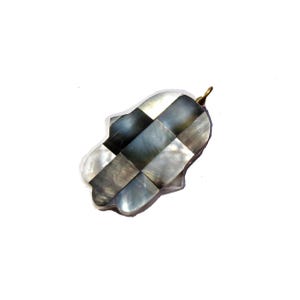 May include: A silver and black Hamsa hand charm made of mother of pearl tiles. The charm has a gold loop at the top for hanging.
