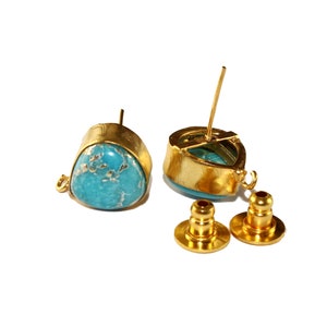 May include: A pair of gold-tone earrings with turquoise stones. The earrings have a teardrop shape and are accented with a small gold loop. The earrings come with a pair of gold-tone backings.