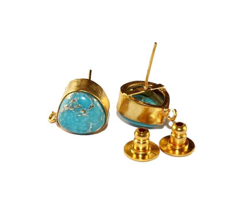 May include: A pair of gold-tone earrings with turquoise stones. The earrings have a teardrop shape and are accented with a small gold loop. The earrings come with a pair of gold-tone backings.