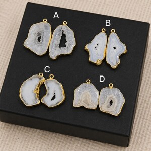 May include: Four pairs of gemstone pendants with gold-colored edges are displayed. The pendants are white and gray with a geode-like appearance. Each pair has a small loop at the top for hanging. The pendants are labeled A, B, C, and D.