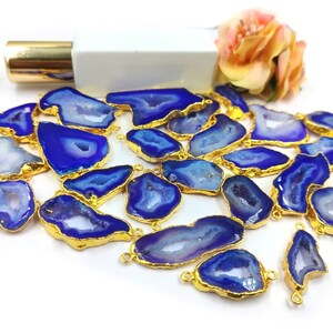 May include: A selection of blue and gold gemstone pendants. The pendants feature a gold-coloured trim and a vibrant blue interior with white and light blue patterns. The gemstones are irregularly shaped and vary in size.