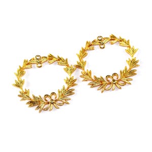 May include: Two gold-coloured wreaths with a bow at the bottom of each wreath.