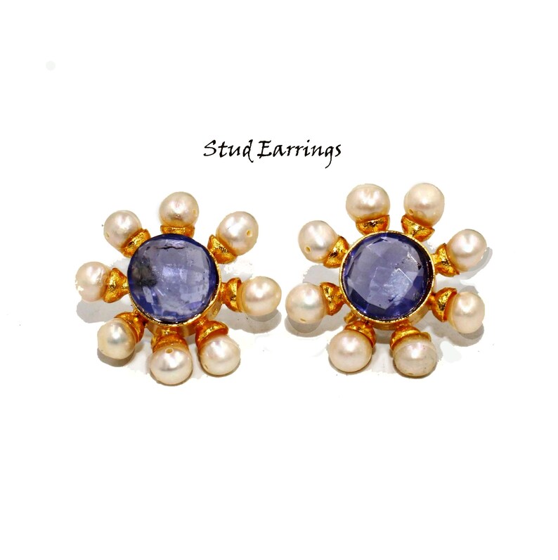 Peut inclure: Une paire de boucles d'oreilles clous en or avec un centre de pierre pr&eacute;cieuse violette et un cercle de perles blanches autour de la pierre pr&eacute;cieuse.