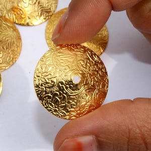 May include: Gold-colored metal embellishments with a floral design and a hole in the center.