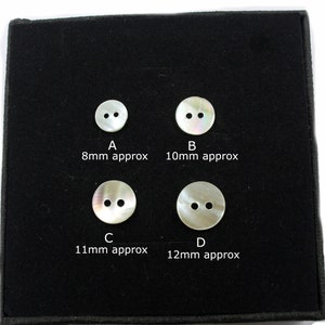 May include: Four white mother of pearl buttons with two holes each, displayed on a black background. The buttons are labeled A, B, C, and D, with approximate measurements in millimeters.