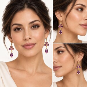 May include: A pair of gold drop earrings featuring three purple amethyst stones arranged in a cluster, with two small round stones at the top and a larger pear-shaped stone dangling below, suspended from a simple gold hook wire mechanism.