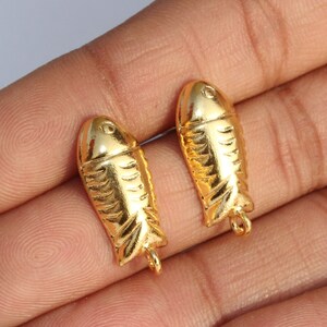 May include: Two gold-colored fish charms with a textured surface. The charms have a loop at the bottom for attaching to jewelry or other crafts.