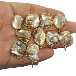 May include: Ten gold-toned metal charms with a natural iridescent mother-of-pearl inlay. The charms are irregularly shaped and have a loop at the top for attaching to jewelry.