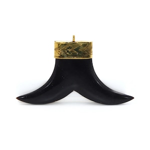 May include: A black horn pendant with a gold-coloured top. The horn is shaped like a crescent moon with a pointed tip. The gold top has a decorative pattern.