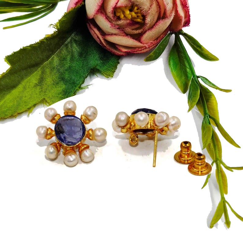 Peut inclure: Une paire de boucles d'oreilles en or avec un centre de pierre pr&eacute;cieuse bleue entour&eacute; de perles blanches. Les boucles d'oreilles ont un fermoir &agrave; tige.