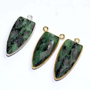 May include: Three green gemstone pendants with gold and silver settings. The pendants are shaped like a teardrop with a pointed tip.